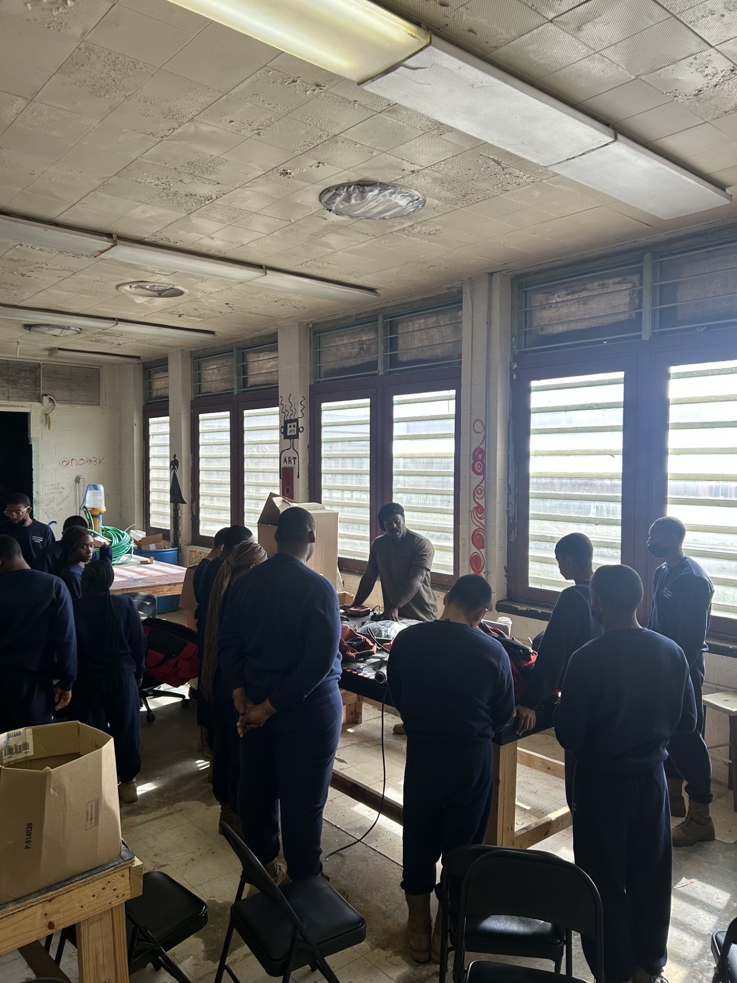 A group of trainees gathered around a workshop table during skilled trades instruction