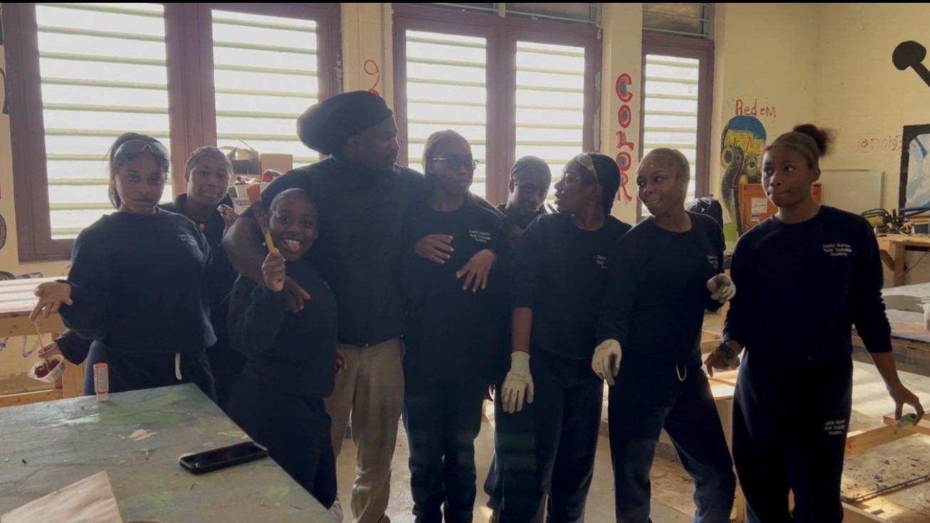 Youth trainees and a mentor standing together in a workshop